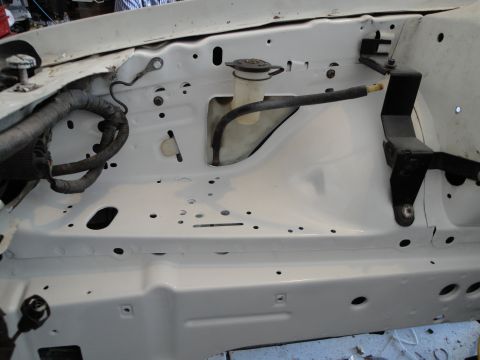 1989 Ford Taurus - The engine bay of a vehicle, showing the windshield washer fluid reservoir and a portion of the wiring harness.