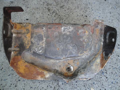 1989 Ford Taurus - A corroded metal component, likely from a vehicle's undercarriage, lies on a speckled concrete surface.