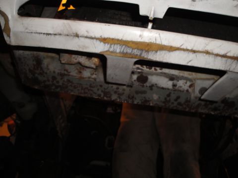 1989 Ford Taurus - Undercarriage view reveals significant rust on metal parts beneath the vehicle's body.