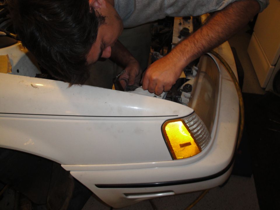 Person working on front corner of white car, near headlight