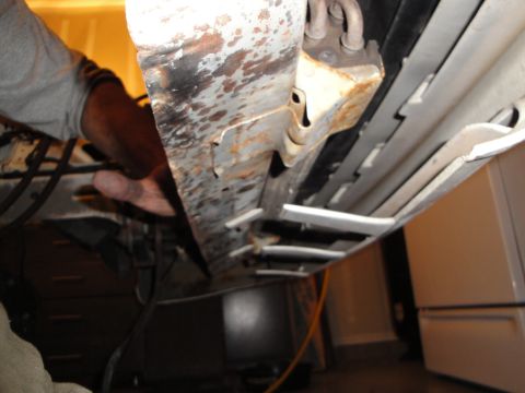 1989 Ford Taurus - Close-up view of a rusted metal frame under a vehicle, with a person's hand inspecting the area.