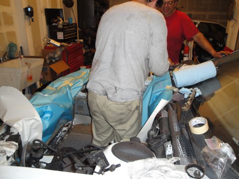 1989 Ford Taurus - Mechanics are working on the engine bay of a car, with various parts covered for protection.