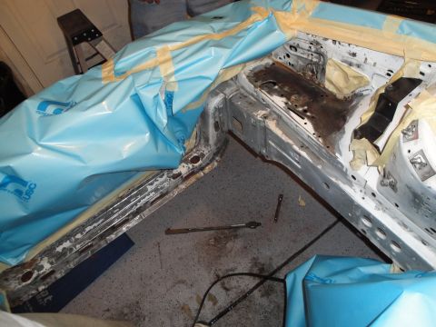 1989 Ford Taurus - The bare frame of a car is visible, covered in protective sheeting and tape, suggesting preparation for work or repair.