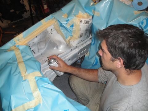 1989 Ford Taurus - A person is spray painting a section of a car's frame, which has been covered with protective sheeting.