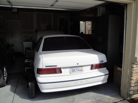 1989 Ford Taurus - Rear view of a white 1989 Ford Taurus SHO parked inside a garage.