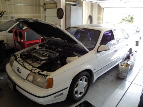 1989 Ford Taurus - White 1989 Ford Taurus sedan in a garage with its hood open, revealing the engine.