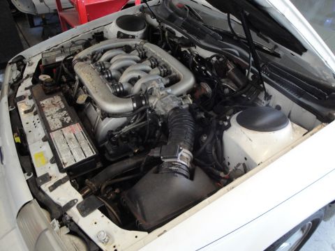 1989 Ford Taurus - The engine bay of a white car is shown, a V6 engine and various components.