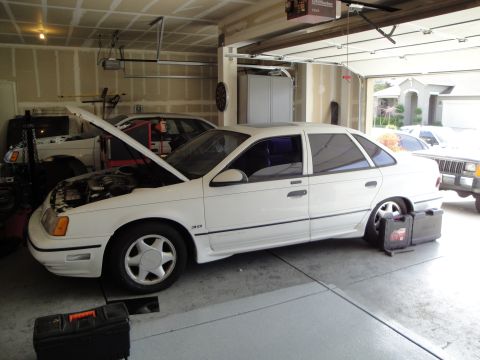 1989 Ford Taurus - White 1989 Ford Taurus with its hood open, parked in a garage next to another vehicle.