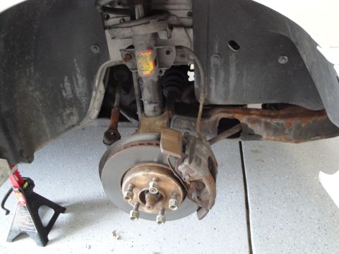 1989 Ford Taurus - Close-up of a car's suspension and brake system, showing wear and rust.