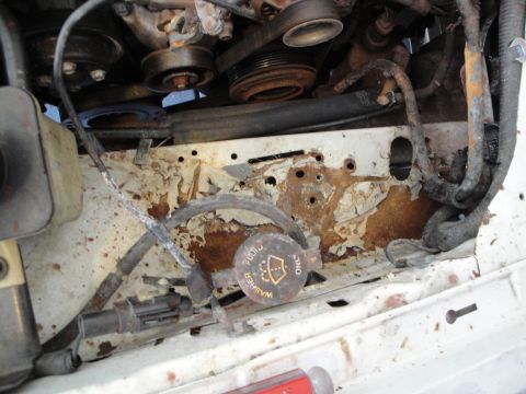1989 Ford Taurus - The engine bay shows significant rust and wear on metal components and wiring.