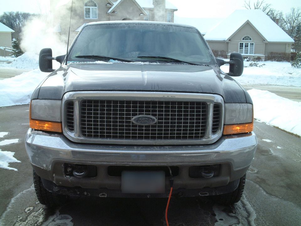 Front view of gray Ford Excursion SUV on snowy driveway with chrome grille