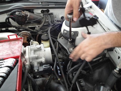 1989 Ford Taurus - Working on engine components, a socket wrench is used to secure a bolt on the mount.