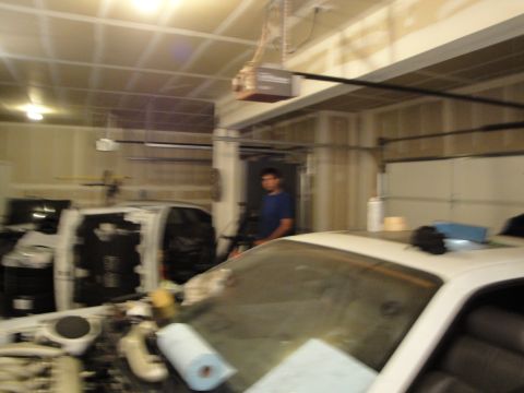 1989 Ford Taurus - Garage scene with a car's interior and engine bay visible, along with a person in the background.