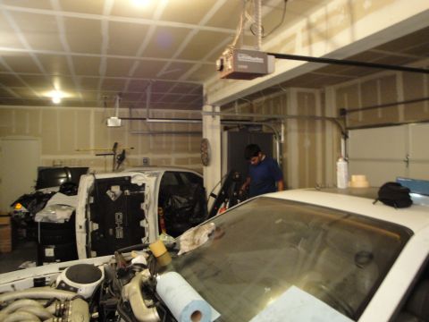 1989 Ford Taurus - A white 1989 Ford Taurus SHO is partially disassembled in a garage, revealing its engine bay.