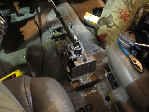 1989 Ford Taurus - The interior of a car reveals a disassembled transmission shifter mechanism, tools, and a bag with graphics.