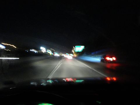 1989 Ford Taurus - Driving on a highway at night with blurred lights from other vehicles and signs.