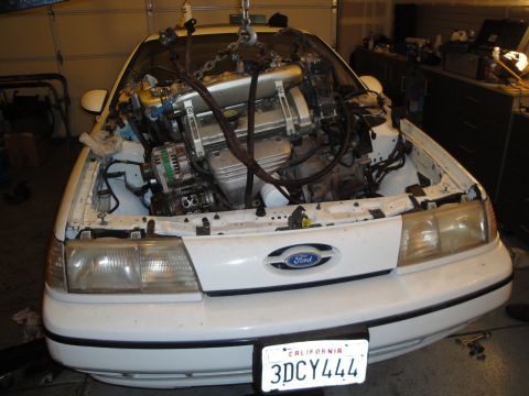 1989 Ford Taurus - White Ford Taurus, likely from the late 1980s, with its engine undergoing removal or replacement.
