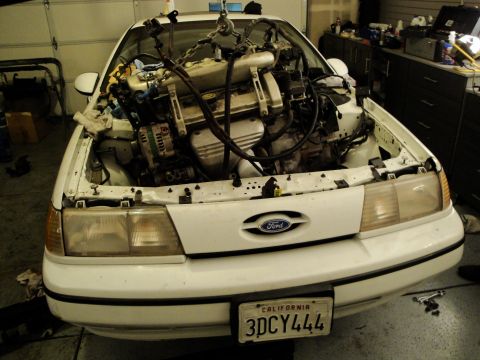 1989 Ford Taurus - The engine bay of a 1989 Ford Taurus is empty as the engine has been removed for service or modification.