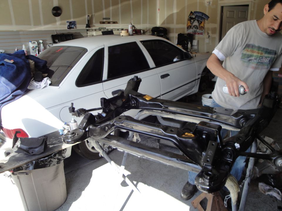 1989 Ford Taurus side view in garage with engine components on stand