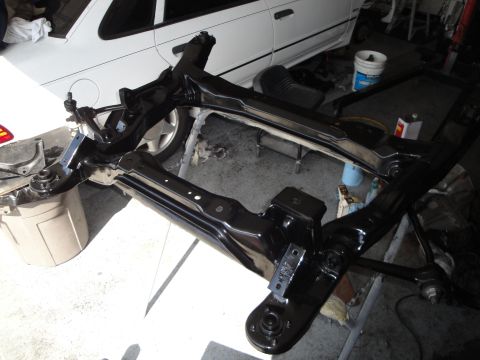 1989 Ford Taurus - A freshly painted black front subframe assembly is laid out, likely for installation or repair.