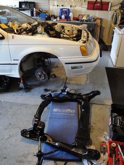 1989 Ford Taurus - The front subframe has been removed from the vehicle, revealing the engine bay and suspension components.