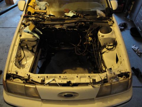 1989 Ford Taurus - The engine bay of a 1989 Ford Taurus is shown with tools and disassembled engine components, indicating an engine swap in progress.