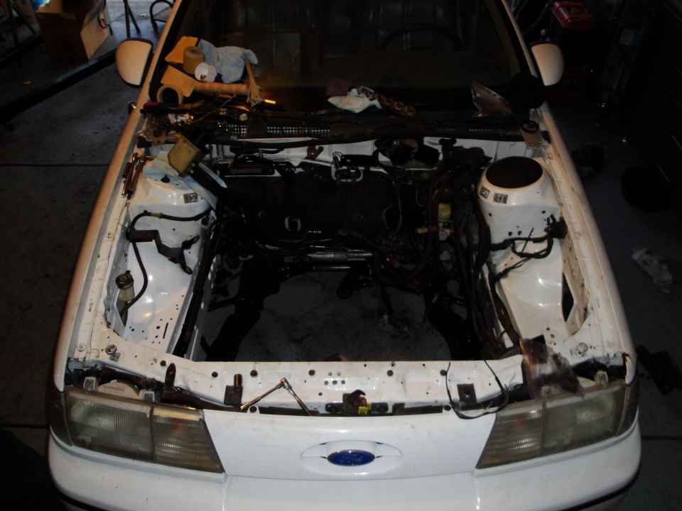 White 1989 Ford Taurus engine bay with engine removed