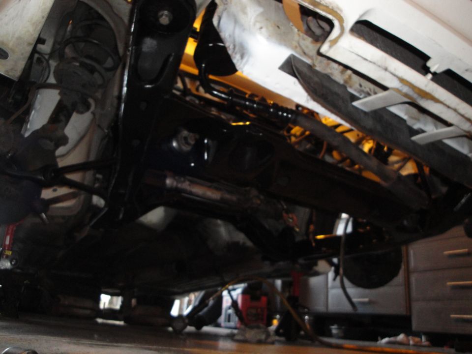 Underside view of a car on jack stands, showing suspension and exhaust components
