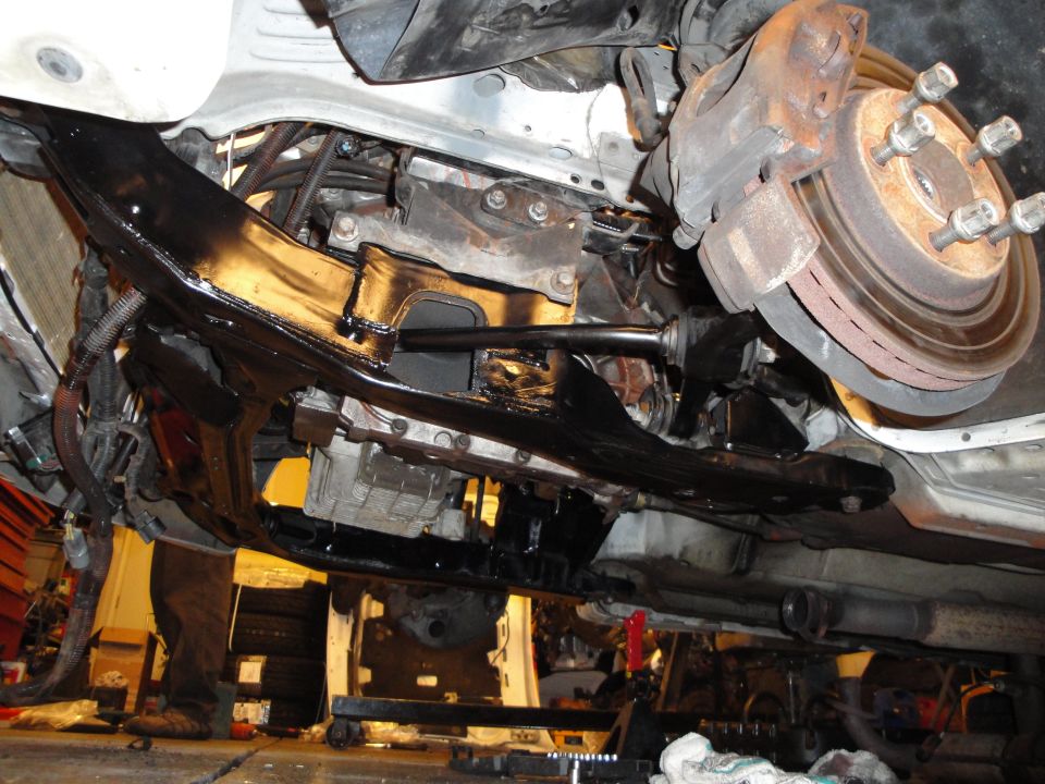 Undercarriage of a vehicle with exposed engine components, brake rotor, and suspension parts