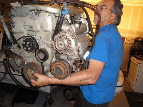 1989 Ford Taurus - Mechanic works on a car engine, focusing on the pulley system.