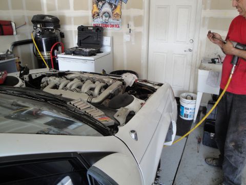 1989 Ford Taurus - Mechanic working on a V6 engine with twin turbochargers in a car's engine bay.