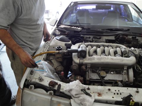 1989 Ford Taurus - A person is working on the engine of a car, with the intake manifold clearly visible.