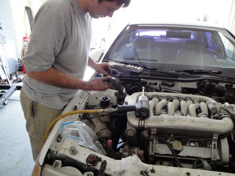 1989 Ford Taurus - Mechanic performs work on a car engine, focusing on the intake manifold.