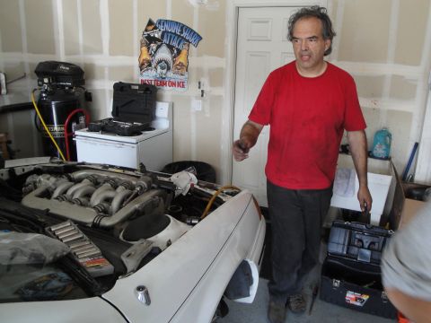 1989 Ford Taurus - The engine bay of a white car is visible, a complex intake manifold and various tools nearby.