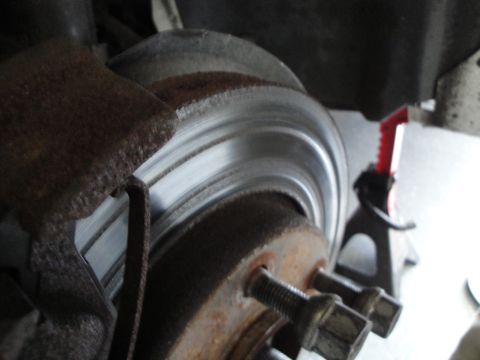 1989 Ford Taurus - A close-up view of a vehicle's brake system, showing the rotor, caliper, and lug nuts.