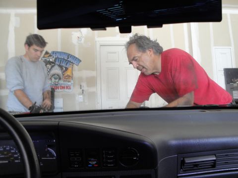 1989 Ford Taurus - Two men are working in a garage, with a shark-themed sign on the wall behind them.