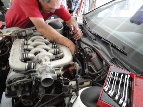 1989 Ford Taurus - A mechanic is actively working on the engine of a vehicle, with tools laid out nearby.
