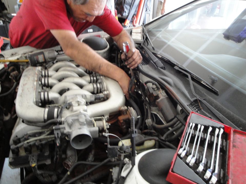Mechanic working on a V-shaped engine in a car's engine bay