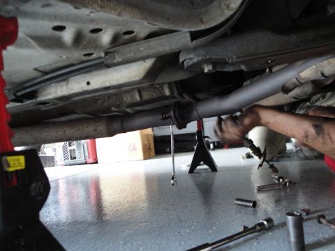 1989 Ford Taurus - Mechanic working on the exhaust system of a car, with tools laid out on the floor.