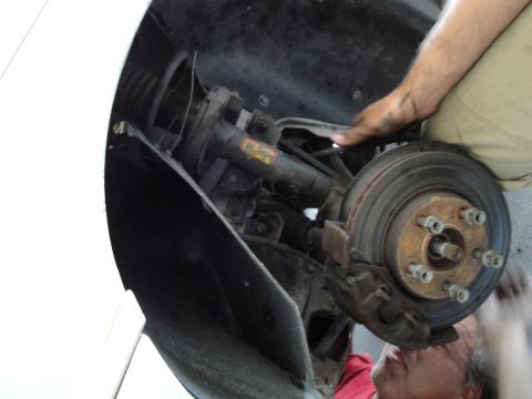 1989 Ford Taurus - Mechanic working on the front wheel brake assembly of a vehicle.
