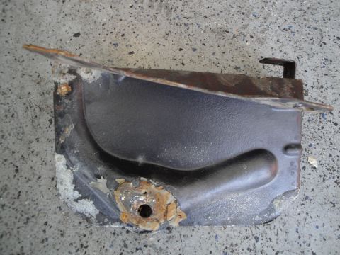 1989 Ford Taurus - A corroded metal bracket, likely from a vehicle's engine bay, lies on a concrete surface.