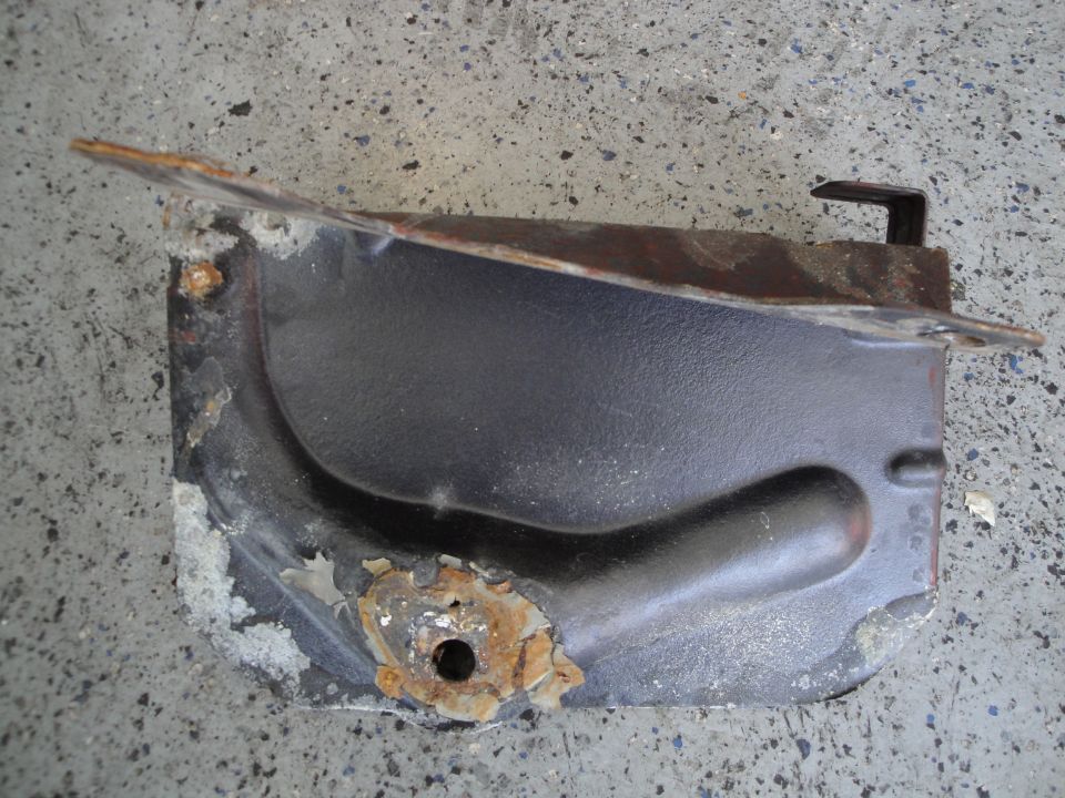Rusted metal bracket with black coating and a mounting hole