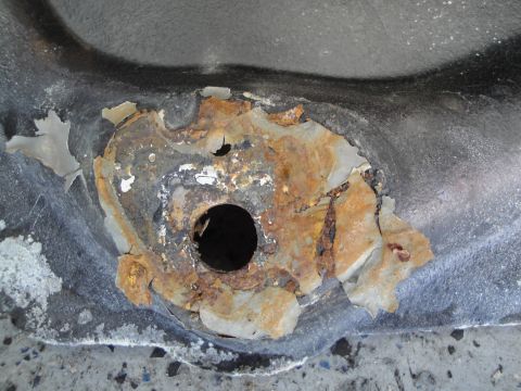 1989 Ford Taurus - Detail of corroded metal showing significant rust and a central opening.