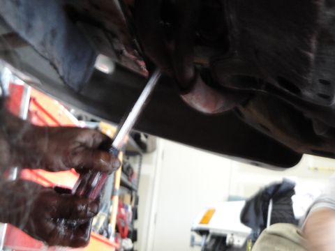1989 Ford Taurus - Mechanic works on a car's exhaust system, with another vehicle in the background.