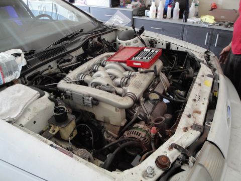 1989 Ford Taurus - The engine bay of a white car is shown with a V6 engine and tools laid out for work.