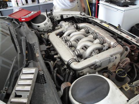 1989 Ford Taurus - The engine bay of a car, showing the engine and intake manifold with tools nearby.