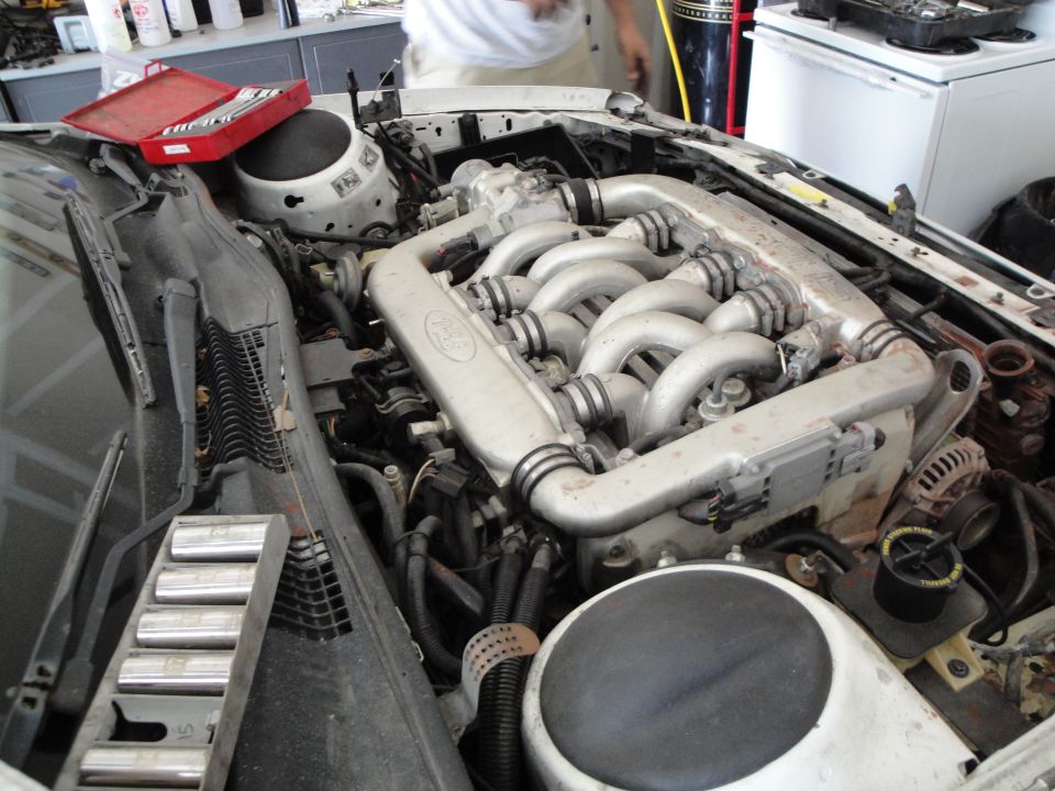 Engine bay with a V-shaped engine and intake manifold, tools on the side