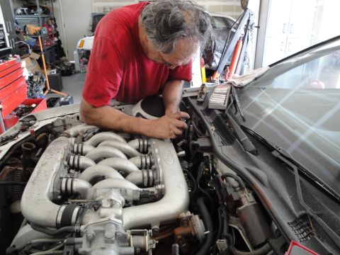 1989 Ford Taurus - Mechanic works on the engine of a 1989 Ford Taurus, likely performing an engine swap or repair.