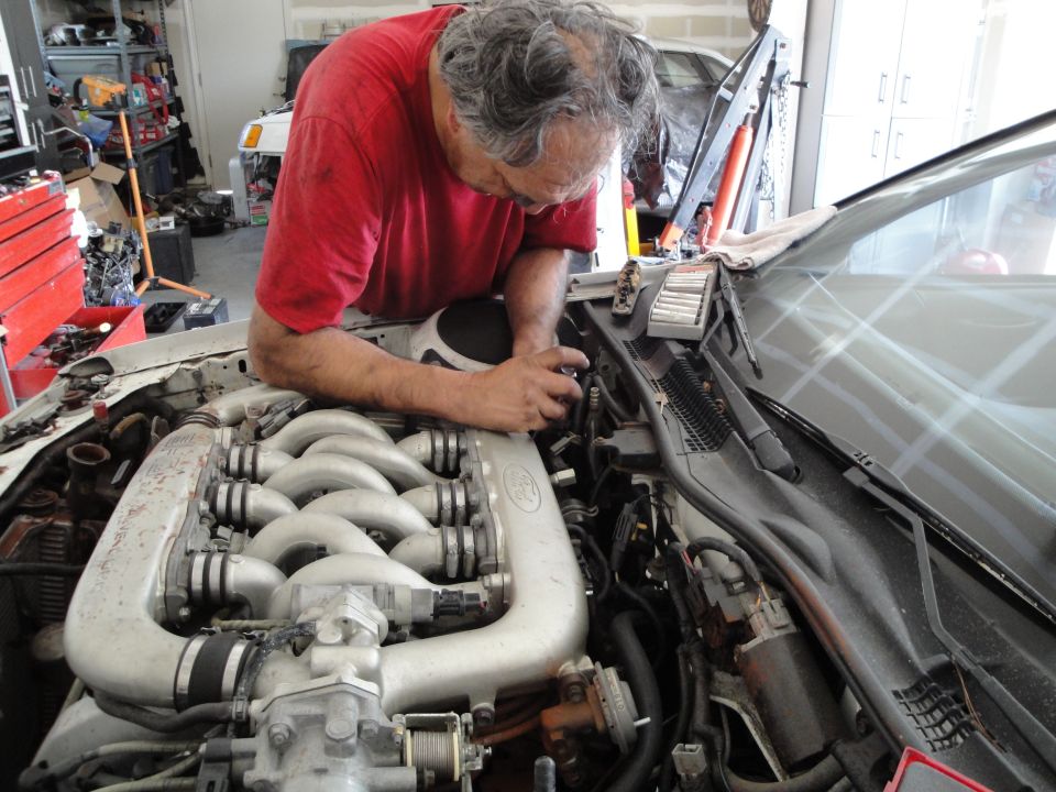 1989 Ford Taurus engine bay with man working on it