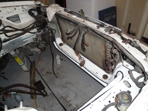 1989 Ford Taurus - The engine bay of a car is shown with the radiator exposed and various components disconnected for maintenance or repair.